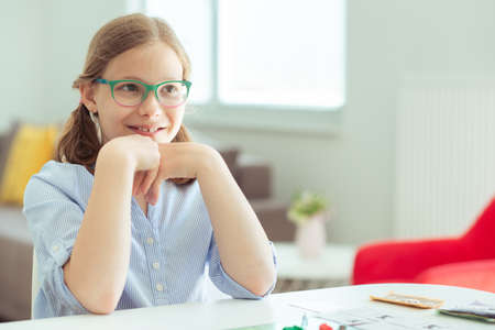 Portrait of pretty teen girl in glasses playing board game with parents at homeの写真素材