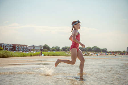 Happy little child girl running and having fun on the beach of Baltic sea at sunny summer dayの写真素材