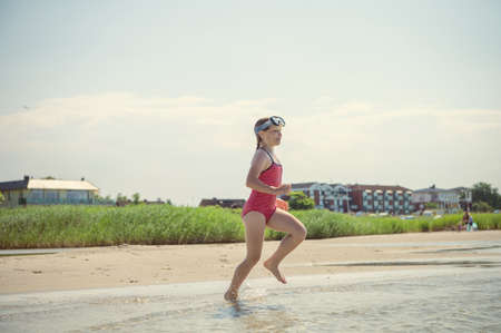 Happy little child girl running and having fun on the beach of Baltic sea at sunny summer dayの写真素材