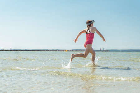 Happy little child girl running and having fun on the beach of Baltic sea at sunny summer dayの写真素材