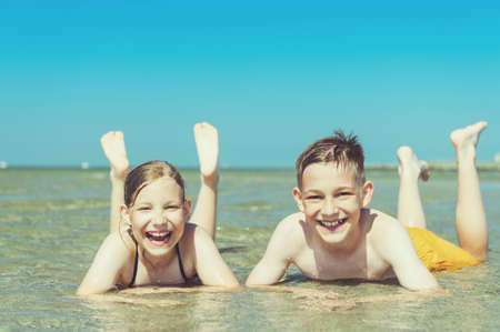 Portrait of two happy siblings teen children liying in water of baltic sea beach at summer holidaysの写真素材