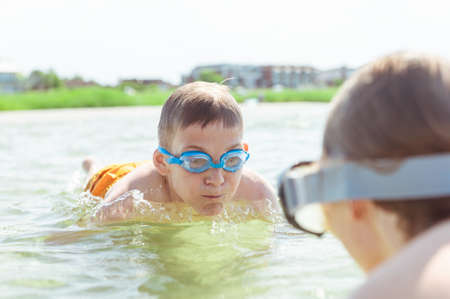 Two happy children playing nad diving in water of Baltic sea at sunny day while summer holidaysの写真素材
