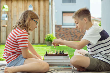 Two happy children playing chess on backyard at sunny day while summer holidaysの写真素材
