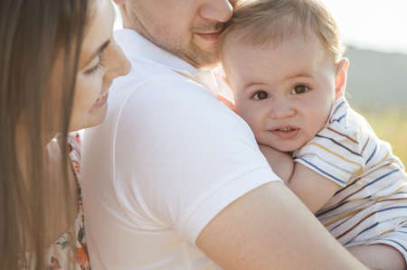 Happy young father holding cute toddler son with nice eyes and enjoying the moment together at sunny lightの写真素材
