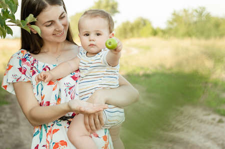 Portrait of happy young mother with her cute baby son joyful exploring the world on field at sunny dayの写真素材