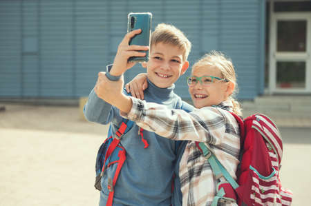 Happy teenagers school children playing and making selfies with cellphone at schoolyard after lessonsの写真素材