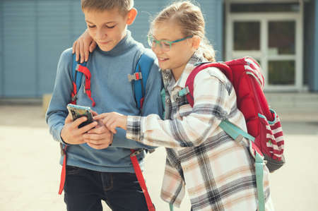 Happy teenagers school children playing and making selfies with cellphone at schoolyard after lessonsの写真素材