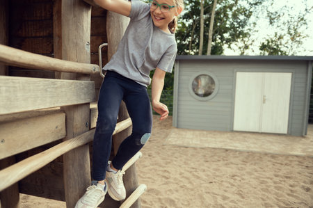 Cute little teen girl playing and climbing at playground at sunny dayの写真素材