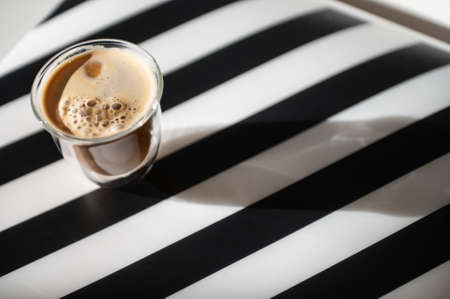 Close Up photo of cup with black coffee and shadow on black and white backgroundの写真素材
