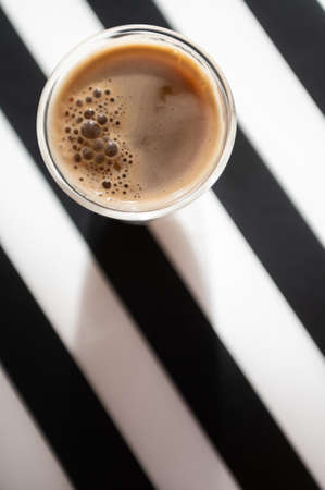 Close Up photo of cup with black coffee and shadow on black and white backgroundの写真素材