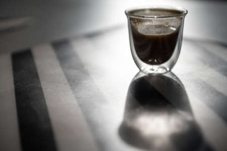 Close Up photo of cup with black coffee and shadow on black and white backgroundの写真素材