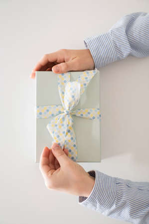 Flat lay photo of beautiful wrapped present box and hands holding gift box on white backgroundの写真素材
