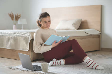 Pretty young woman working with laptop at cozy bedroom at home