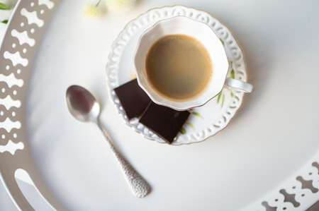 Stylish cup of espresso black coffee with black chocolate on beautiful white tray at cafeteria