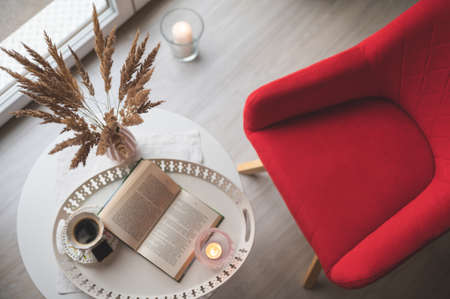 Overview photo of table with coffee book and red chair near the windowの写真素材