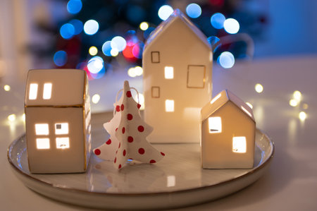 Christmas decoration with little Scandinavian hauses, Christmas tree, and magic bokeh lights on backgroundの写真素材