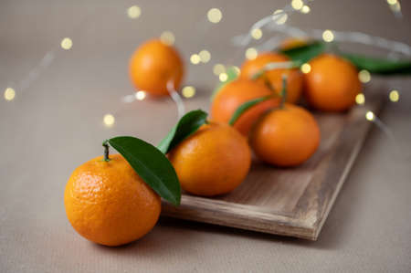 Closeup photo of juicy orange mandarins with fresh green leaves with bokeh on backgroundの写真素材