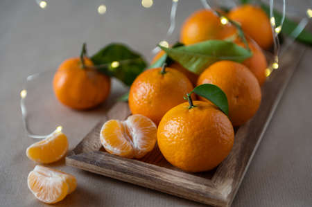 Closeup photo of juicy orange mandarins with fresh green leaves with bokeh on backgroundの写真素材