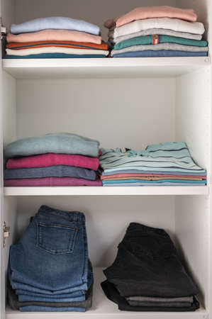 Pastel clothes neatly folded on shelves in wardrobeの写真素材