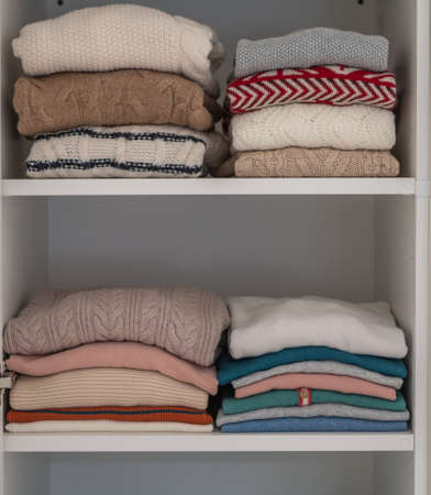 Pastel clothes neatly folded on shelves in wardrobeの写真素材