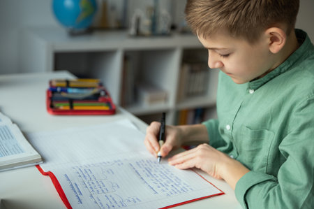 Diligent tenn student sitting at table and studying at home during online courseの写真素材