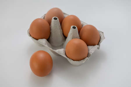 Closeup of fresh brown eggs in paper box over white backgroundの写真素材