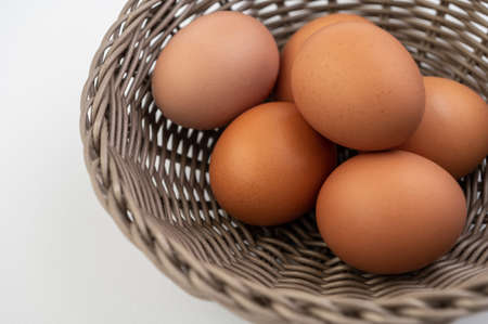 Closeup of fresh brown eggs in Easter basket over white backgroundの写真素材