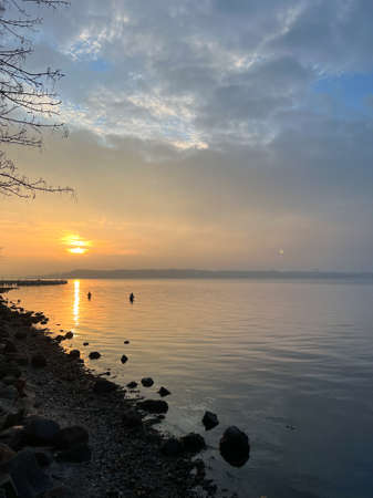 Serene scene of two fishermen in water over dramatic sunset in Baltc seaの写真素材