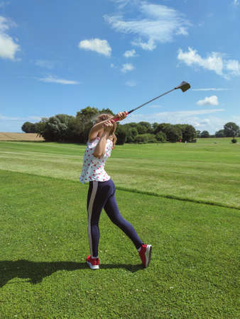 Cute teen girl playing golf on green grass at golf club in summerの写真素材