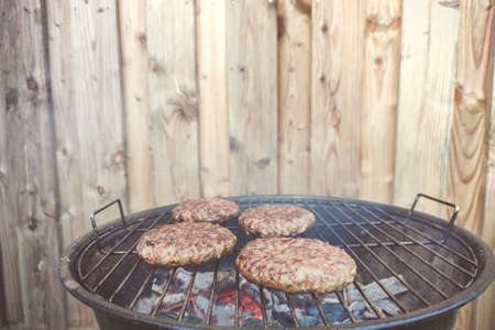 Close up photos of big delicious hamburger on grid barbecue  at backyard in summerの写真素材