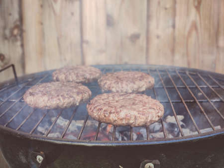 Close up photos of big delicious hamburger on grid barbecue  at backyard in summerの写真素材