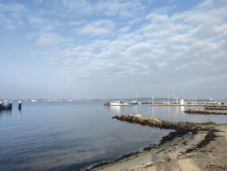 Sunset scene over Baltic sea with empty harbor and small lighthouseの写真素材
