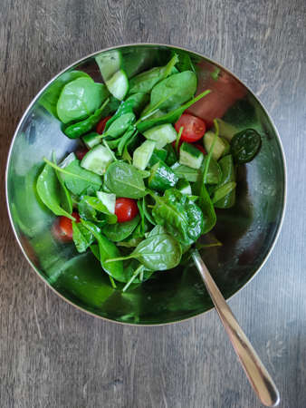 Top view photo of green healthy salad with other colorful vegetables such as cherry tomato and cucumberの写真素材
