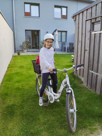 Pretty teen girl in helmet on bike in backyard at summer dayの写真素材