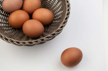Closeup of fresh brown eggs in Easter basket over white background. View from aboveの写真素材