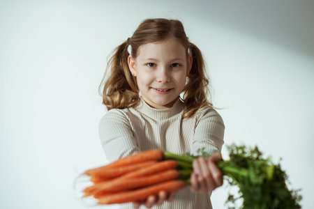 Cute teen girl holding a bunch of fresh orange carrots with green leavesの写真素材