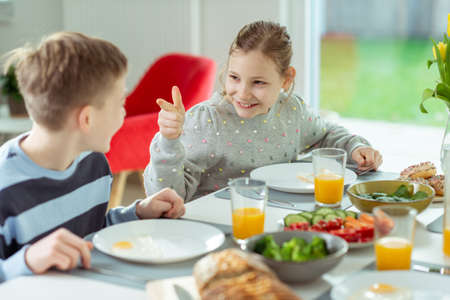 Teen children talking during healthy breakfast at home in the morning before going to schoolの写真素材