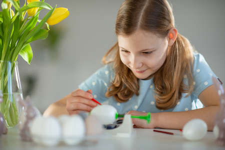 Portrait of pretty happy little girl painting eggs for easter celebtationの写真素材