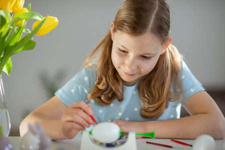 Cute little girl painting easter eggs at homeの写真素材