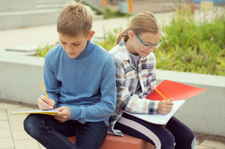 Male and female classmates studying in the school yard after classes