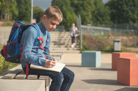 Teen schoolboy with backpack sitting in the school yard after classesの写真素材