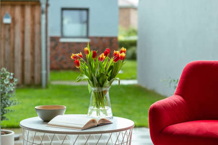 Fresh spring tulips in glass vase and a cup of coffee with a book for readingの写真素材