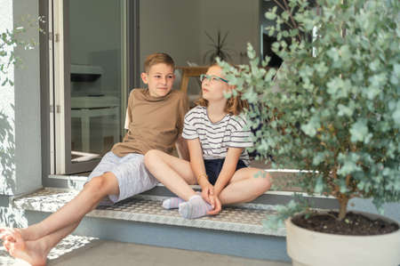 Two happy teenage siblings having fun together sitting on porch of terrace