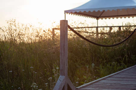 Wooden terrace with sun umbrella at sunset yellow light at summer eveningの写真素材