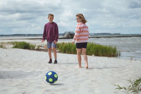 Happy teen children joyful playing voleyball on white summer beach at summer holidaysの写真素材