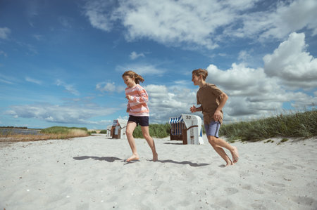Happy teen children running and having fun on beach with white sand at summer holidaysの写真素材