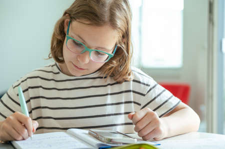 Blonde teen schoolgirl doing her homework after classesの写真素材