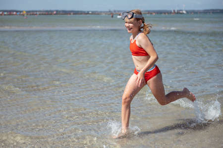 Happy child girl running and enjoying summer in water at sea at vocationの写真素材