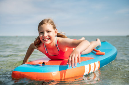 Happy teen girl lying on stand up paddle board and enjoy waterの写真素材
