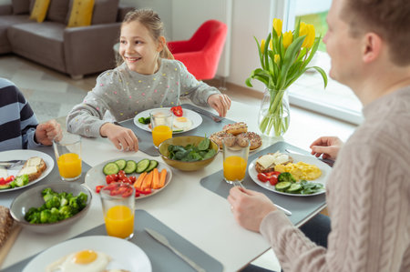 Teen children and their father talking during healthy breakfast at home in the morning before going to schoolの写真素材